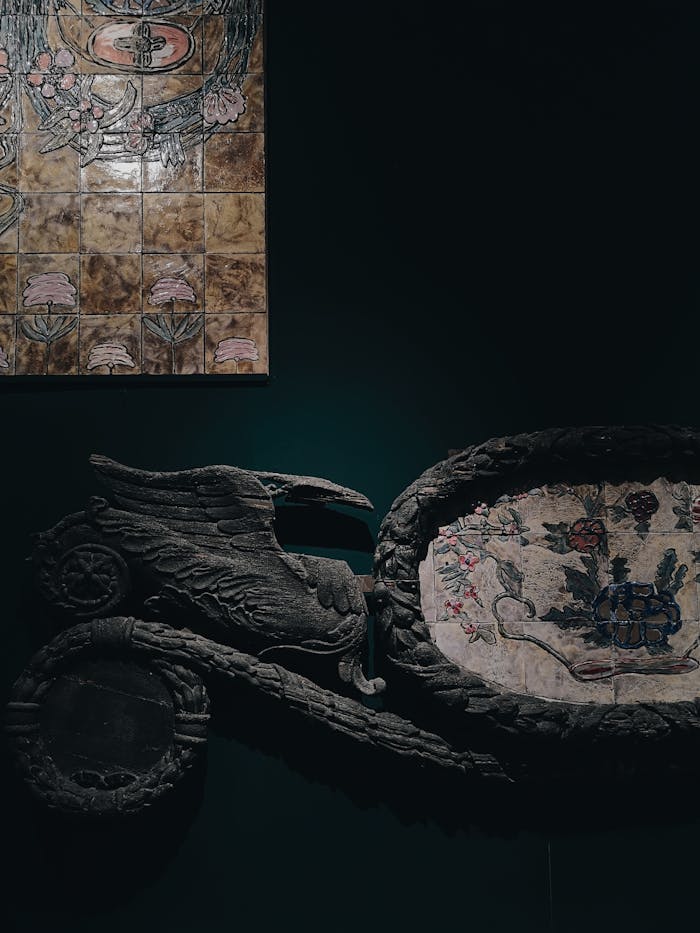 Detailed view of intricate ceramics and sculptures on display in a dimly lit art gallery setting.